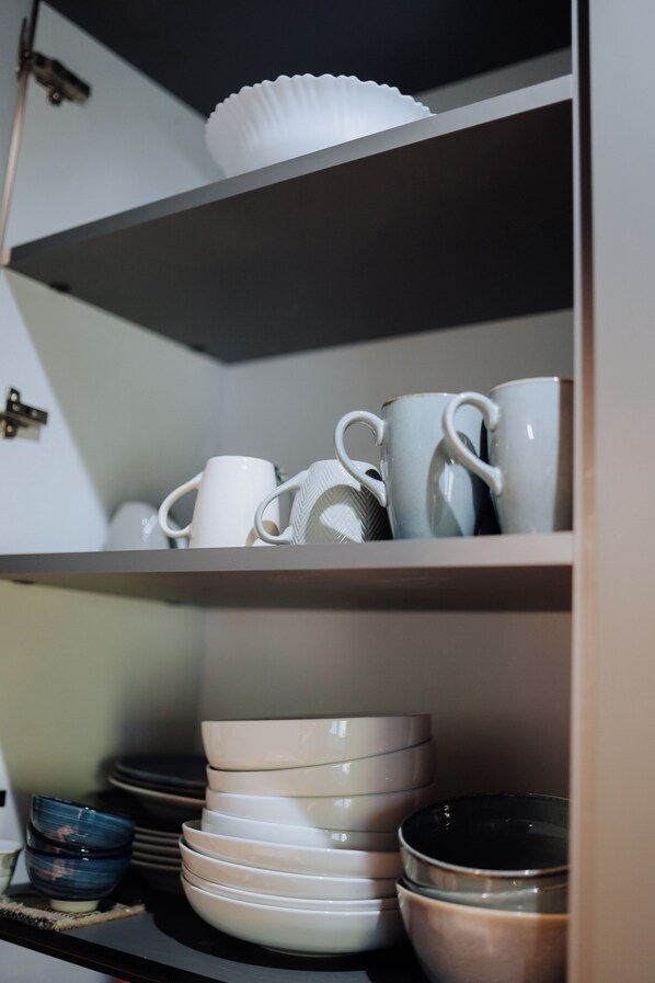 A shelf with stacked white and blue bowls, plates, and a white paper cup.