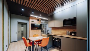Une cuisine moderne avec un plafond en bois, des appareils électroménagers intégrés et un coin repas doté de chaises orange.