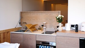 Une cuisine moderne avec un plan de travail en bois, des appareils électroménagers intégrés et un grand miroir au-dessus de l’évier.
