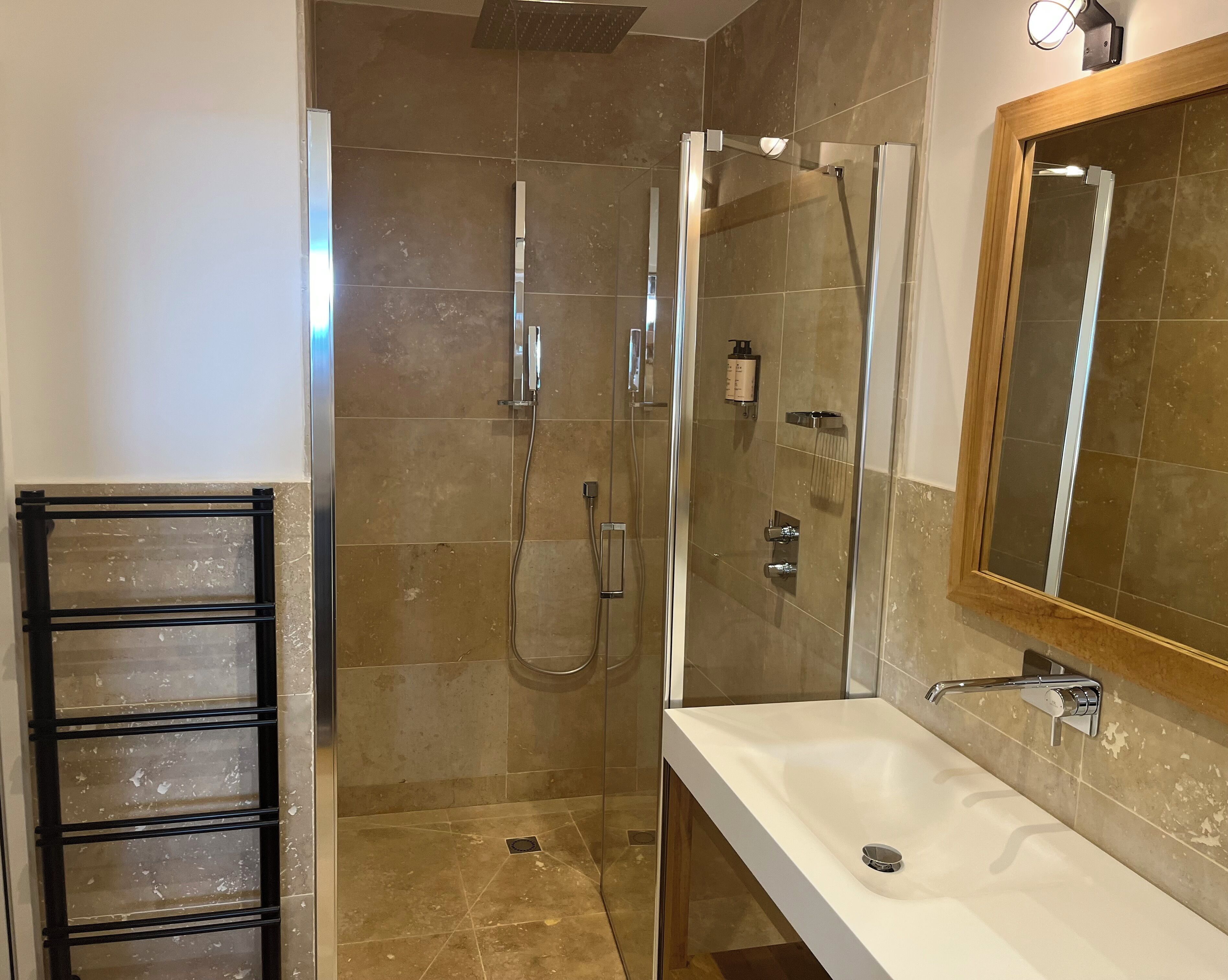 A modern bathroom with a glass-enclosed shower, a white sink, and a large mirror.