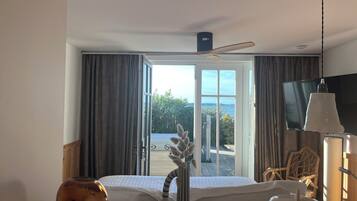 Ein Hotelzimmer mit Bett, Fernseher, Deckenventilator und Blick ins Freie.
