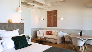 Une chambre d’hôtel moderne équipée d’un lit, d’un canapé, d’une table à manger et d’une œuvre d’art accrochée au mur.