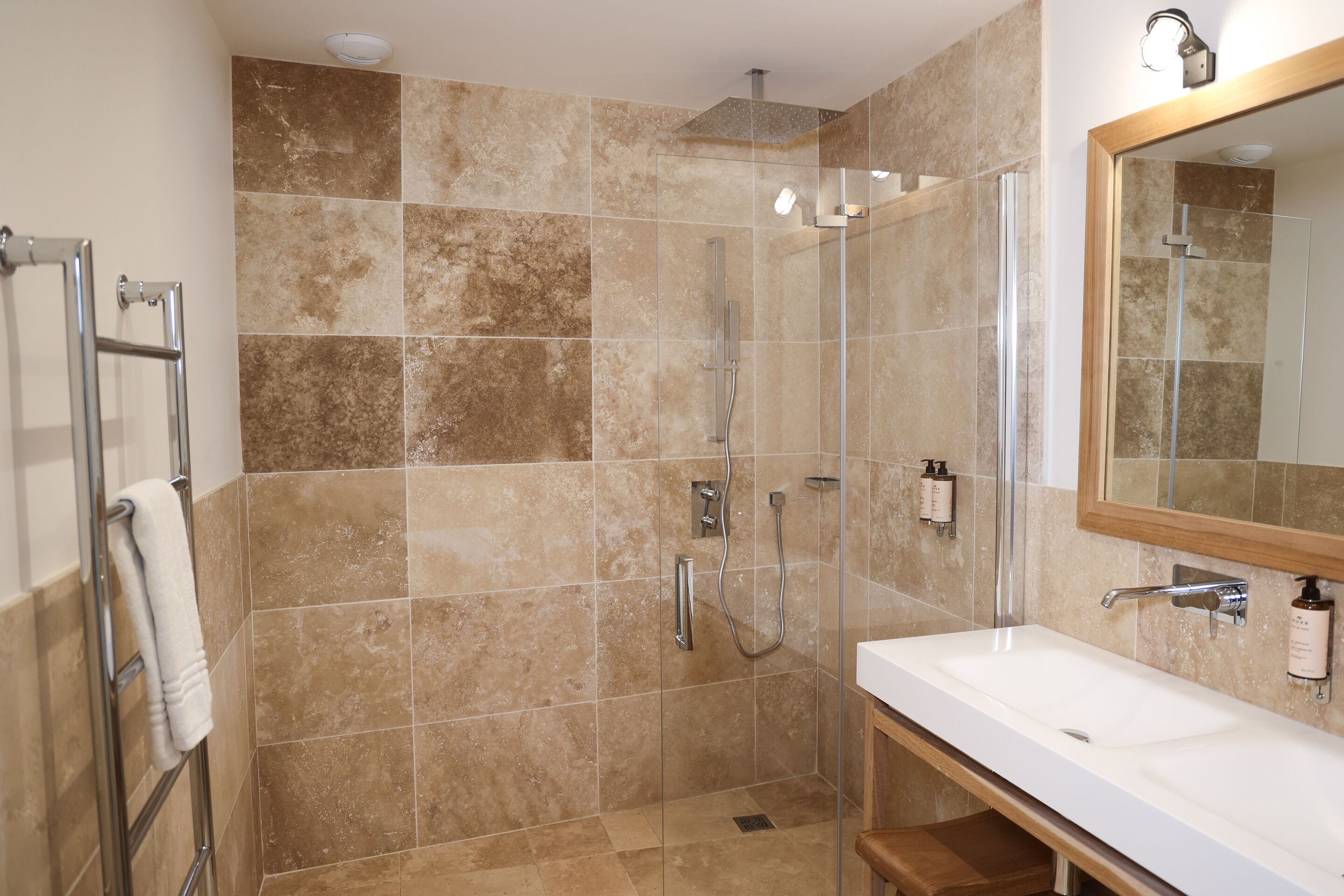 A modern bathroom with a glass-enclosed shower, a white sink, and a large mirror.