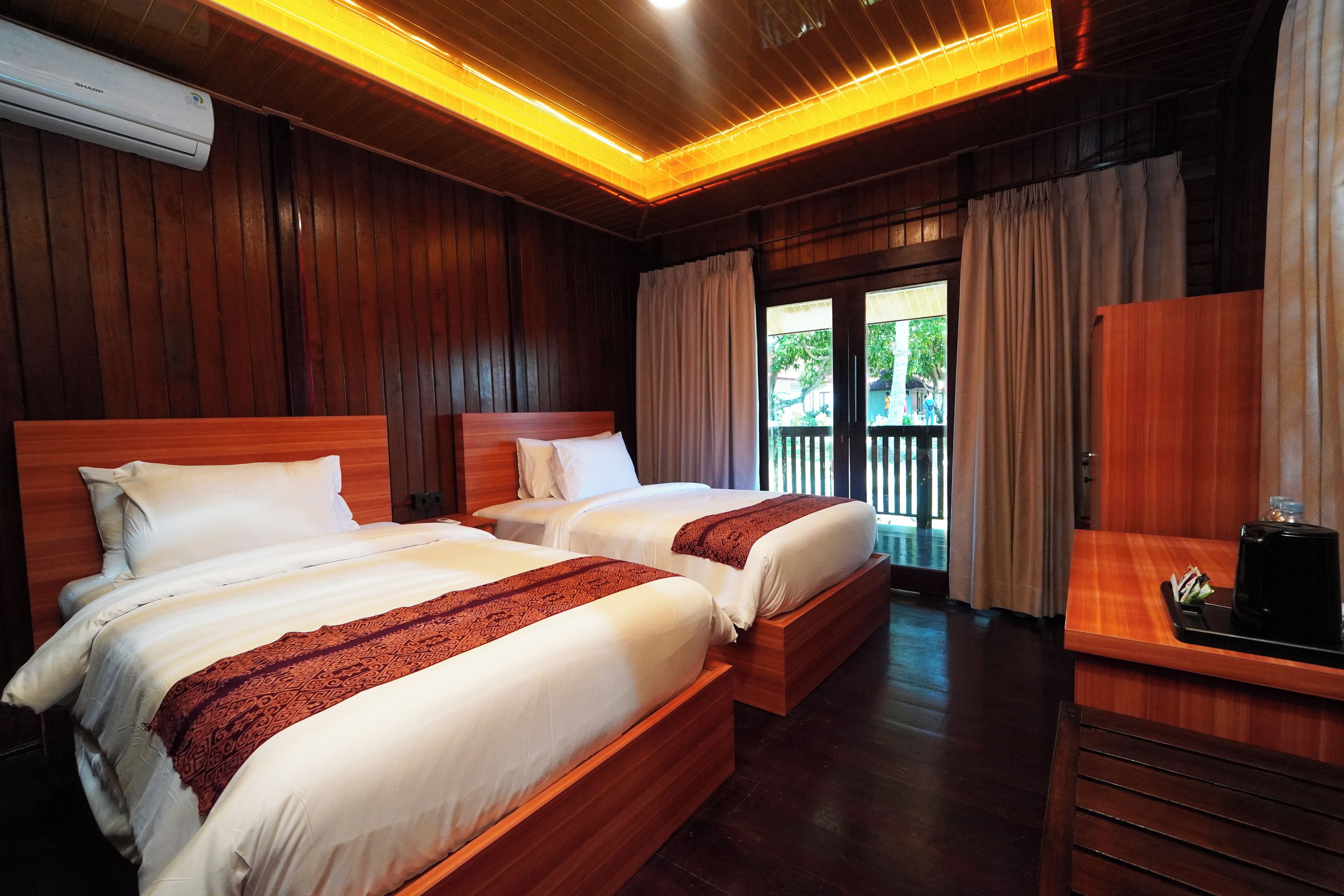Une chambre d’hôtel avec deux lits, un plafond en bois, une vue sur l’extérieur et un bureau avec une machine à café.