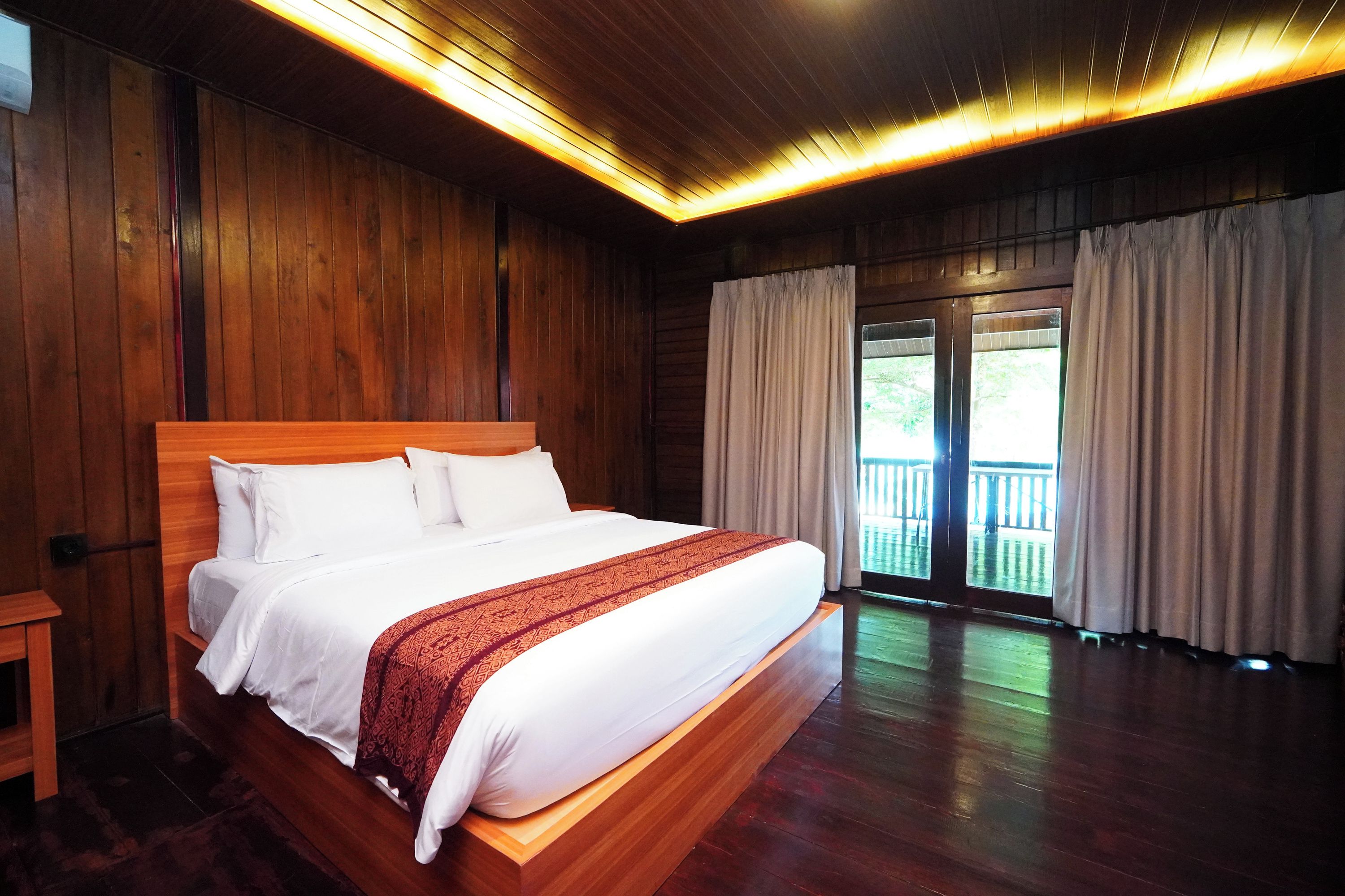 A large bed with a wooden headboard, white bedding, and a patterned throw.