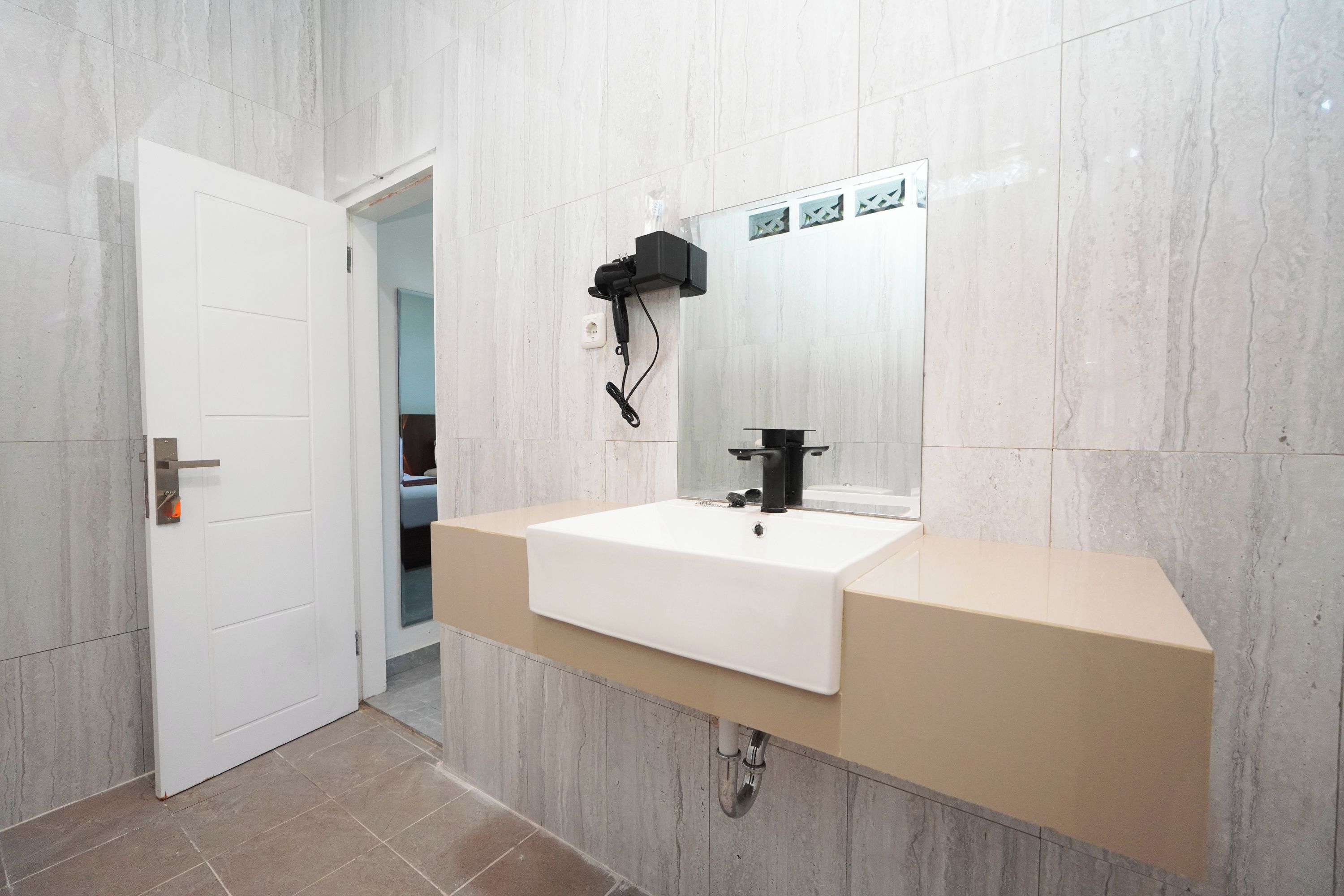 Une salle de bain avec un lavabo blanc, un miroir et une pomme de douche fixée au mur.