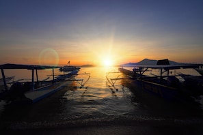 A sunset over a body of water with boats docked. - PS Bunaken Resort & Dive (Pulau Bunaken)