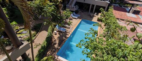 A rooftop pool area with lounge chairs and a staircase leading to an upper level.