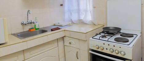 A compact kitchen with a stove, oven, and a single sink.