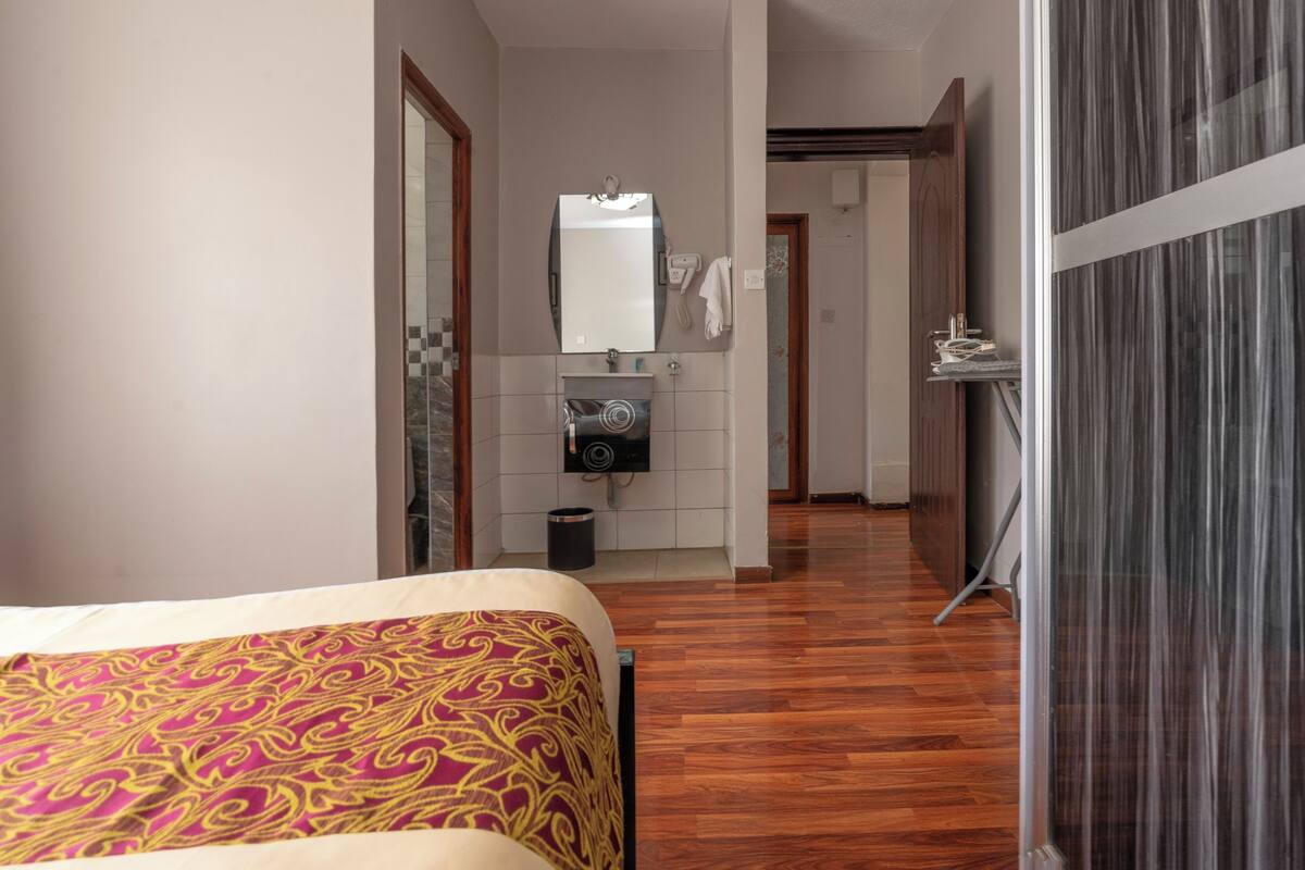 Habitación de hotel con cama, baño con espejo, lavabo y zona de ducha.