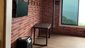 A room with a brick wall, a window, a table, and a speaker. - Manjushree Homestay (Darjeeling)