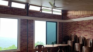 A spacious room with a high ceiling, large windows, and a brick wall. - Manjushree Homestay (Darjeeling)