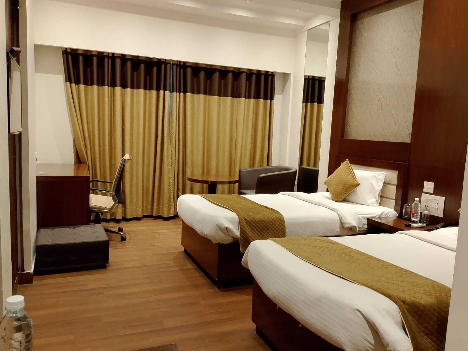 Una habitación de hotel con dos camas, un escritorio, una silla y una mesita.