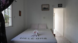 A room with a bed, a welcome mat, and a framed picture on the wall. - Poolside Seaview Studio With Infinity Pool & Overwater Deck Near Airport, 1st FL (Belize City)