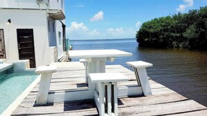 A wooden deck with a table and benches overlooking a body of water. - Poolside Seaview Studio With Infinity Pool & Overwater Deck Near Airport, 1st FL (Belize City)
