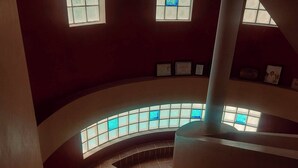 Una escalera curva con barandilla de cristal, que baja a un nivel inferior.