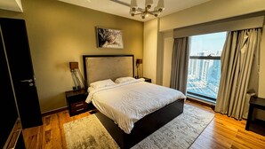 Un dormitorio moderno con una cama grande, vista a la ciudad y un candelabro.