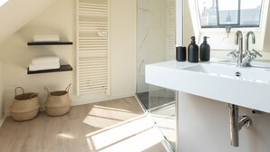 Une salle de bain moderne dotée d’un puits de lumière, d’un grand miroir et d’un meuble-lavabo blanc.