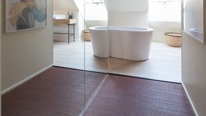 Une salle de bain moderne avec une baignoire sur pieds, des fenêtres de toit et des œuvres d’art accrochées aux murs.