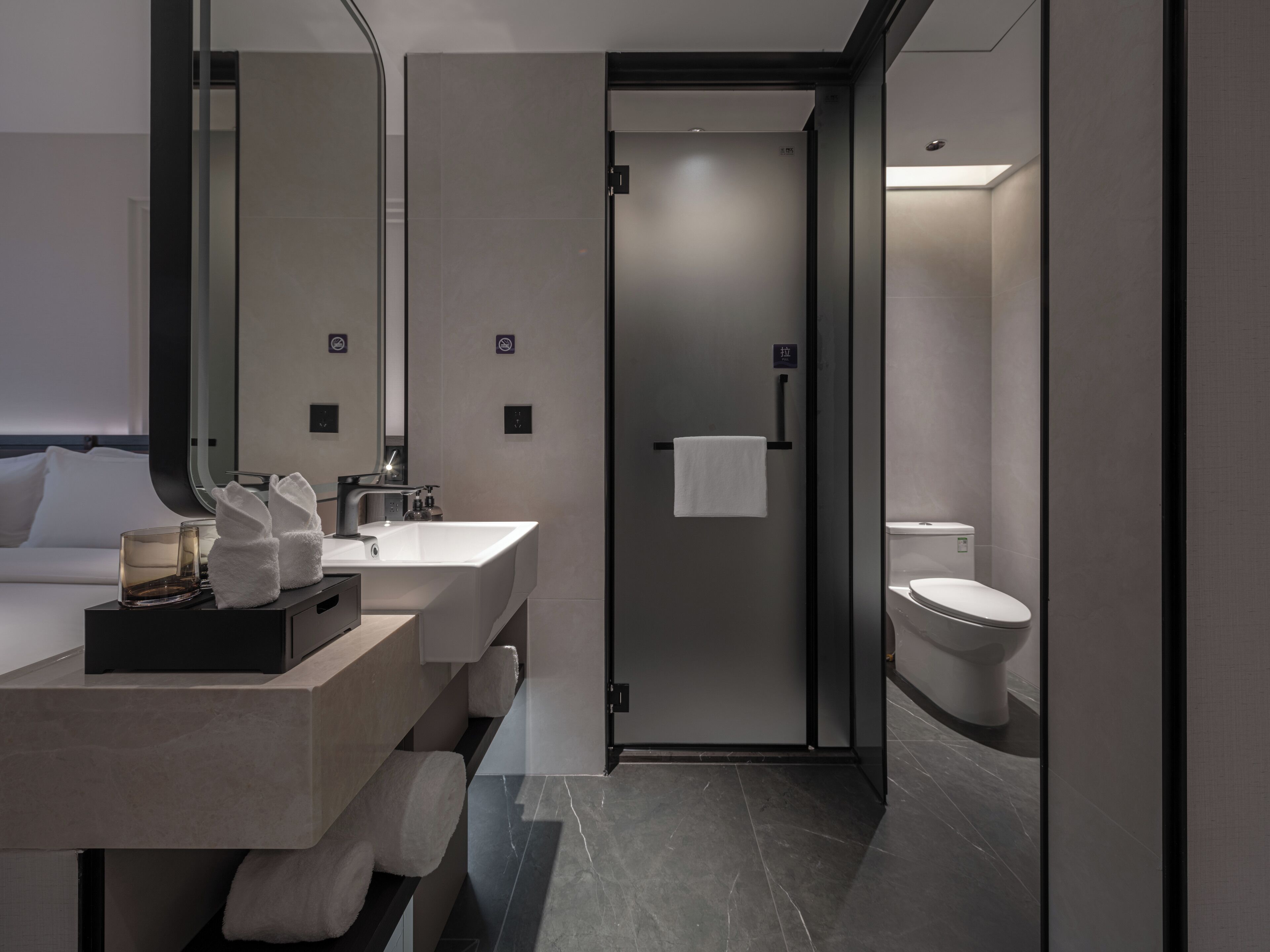 Un baño moderno con un espejo grande, un lavabo, un inodoro y una zona de ducha.
