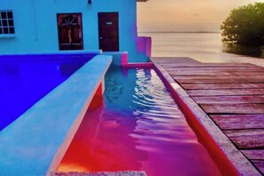 Ein Pool mit Holzterrasse und einem Gebäude im Hintergrund.