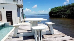 A wooden deck with a pool and a table and benches. - Sea Belize Relaxing Studio w Sea View Pool & Overwater Deck Near Airport, 1st FL (Belize City)