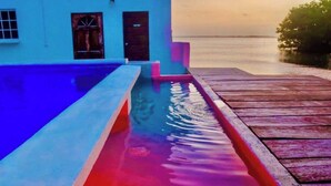 Una piscina con cubierta de madera y un edificio al fondo.