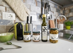 A kitchen counter with various jars of olives, a bottle of wine, and kitchen utensils. - Maddalena Holiday House (Imperia)