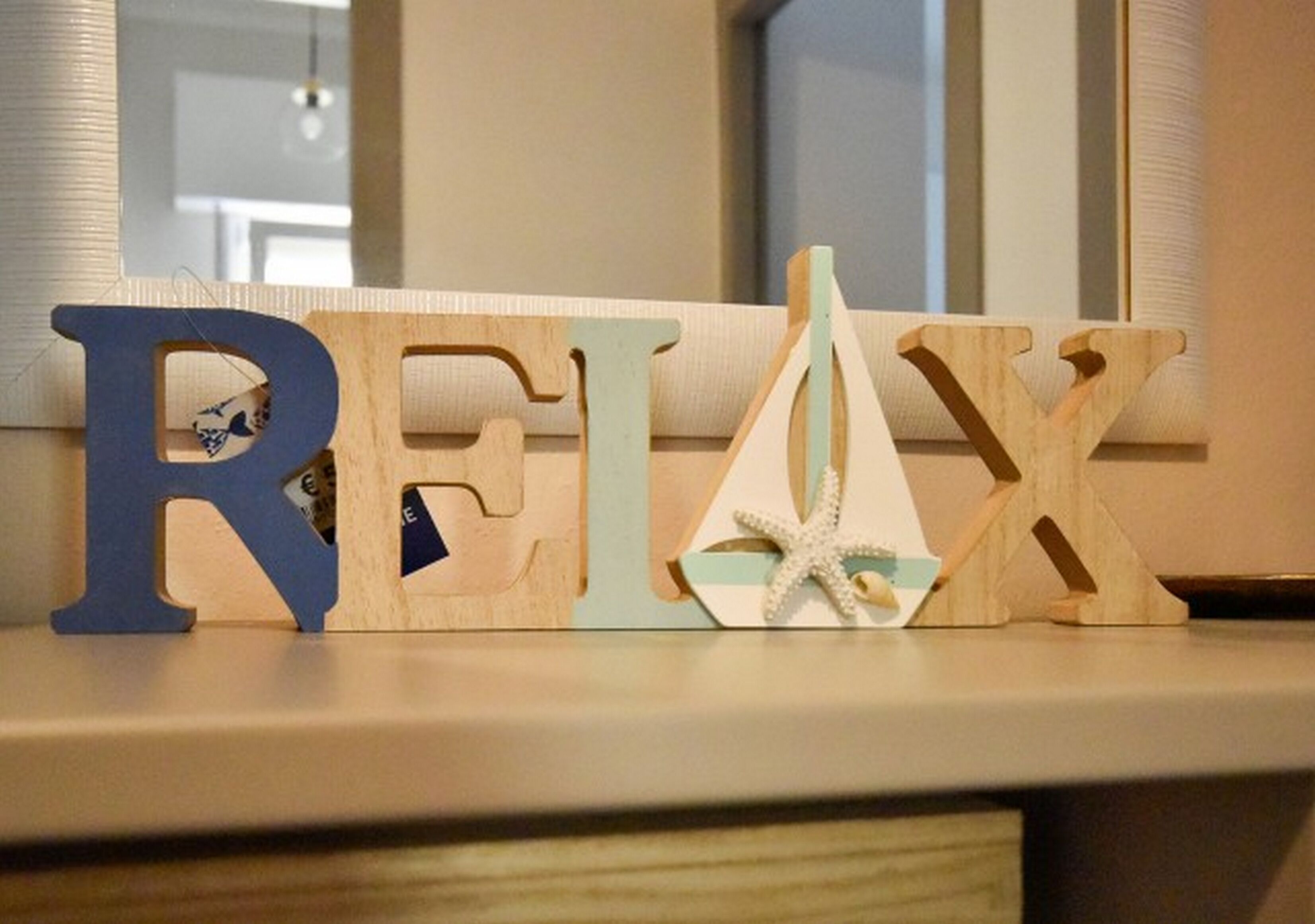 Wooden letters spelling "RELAX" with a starfish decoration between the 'L' and 'X'.