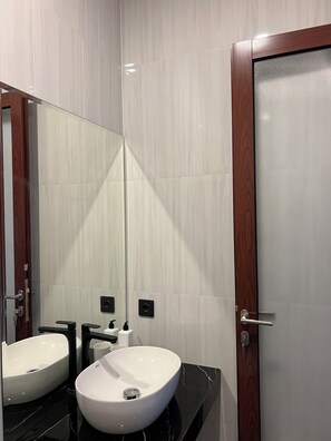 Een badkamer met twee wasbakken, een spiegel en een deur.