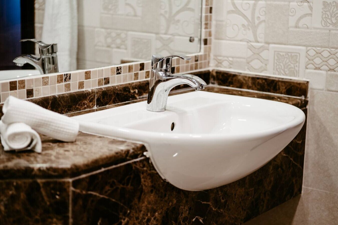 A bathroom with a white sink, a towel, and a marble countertop.