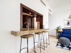 A modern kitchen with a granite countertop, three bar stools, and a built-in bar area.