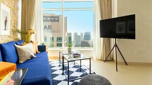 A modern living room with a blue sofa, a coffee table, and a flat-screen TV. - Spacious 2BR in Downtown  | High Floor | 8 Guests (Dubai)