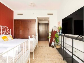 Ein modernes Schlafzimmer mit Bett, Kleiderschrank, Fernseher und einem kleinen Balkon.