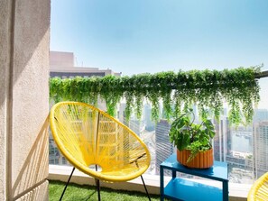 Ein Balkon mit gelbem Stuhl, einem kleinen Tisch und einem Blumentopf.