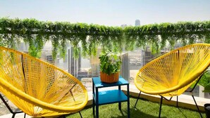 A balcony with two yellow chairs, a small table, and a potted plant. - Spacious 2BR in Downtown  | High Floor | 8 Guests (Dubai)