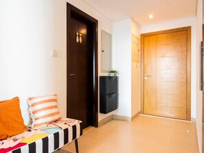 Una habitación de hotel con una cama, una puerta de madera, un mueble pequeño y un televisor instalado en la pared.