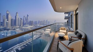 Un balcon moderne offrant une vue sur la ville, doté d’une balustrade en verre et de mobilier contemporain.