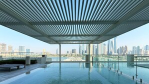 Une piscine intérieure à débordement offrant une vue sur le panorama urbain, un espace salon couvert et un design architectural moderne.