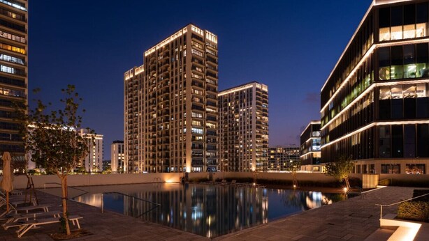 A modern high-rise building complex with a reflective pool in the foreground.