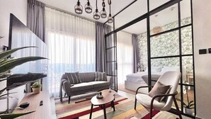 A modern living room with a sofa, armchair, coffee table, and a large window with curtains.