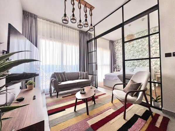 Una sala de estar moderna con sofá, sillón, mesa de centro y un ventanal con cortinas.