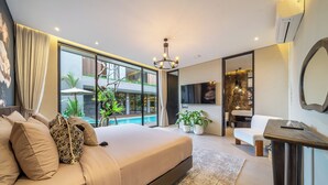 Quarto moderno com uma cama grande, uma mesinha, uma cadeira, uma janela ampla e vista para uma piscina e vegetação lá fora.
