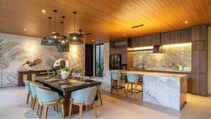 Cozinha moderna com teto de madeira, bancadas de mármore e uma ilha central com banquetas.