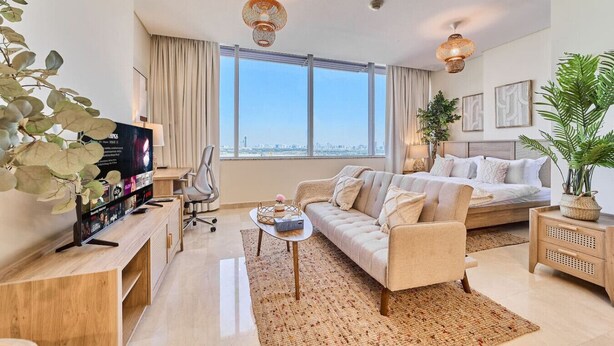 Een moderne woonkamer met een groot raam, een bank, een bed, een televisie en sierplanten.