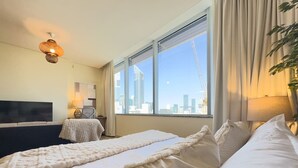 Een hotelkamer met een groot bed, een televisie, een bureau en een raam met uitzicht op de stad.