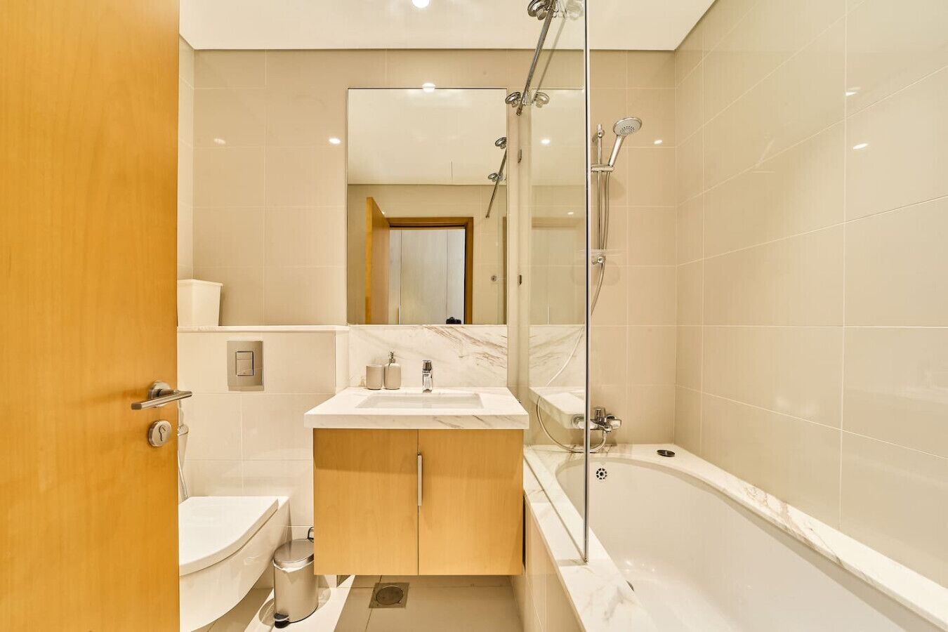 Een moderne badkamer met een badkuip, een douche met glazen wanden, een wastafel met spiegel en een toilet.