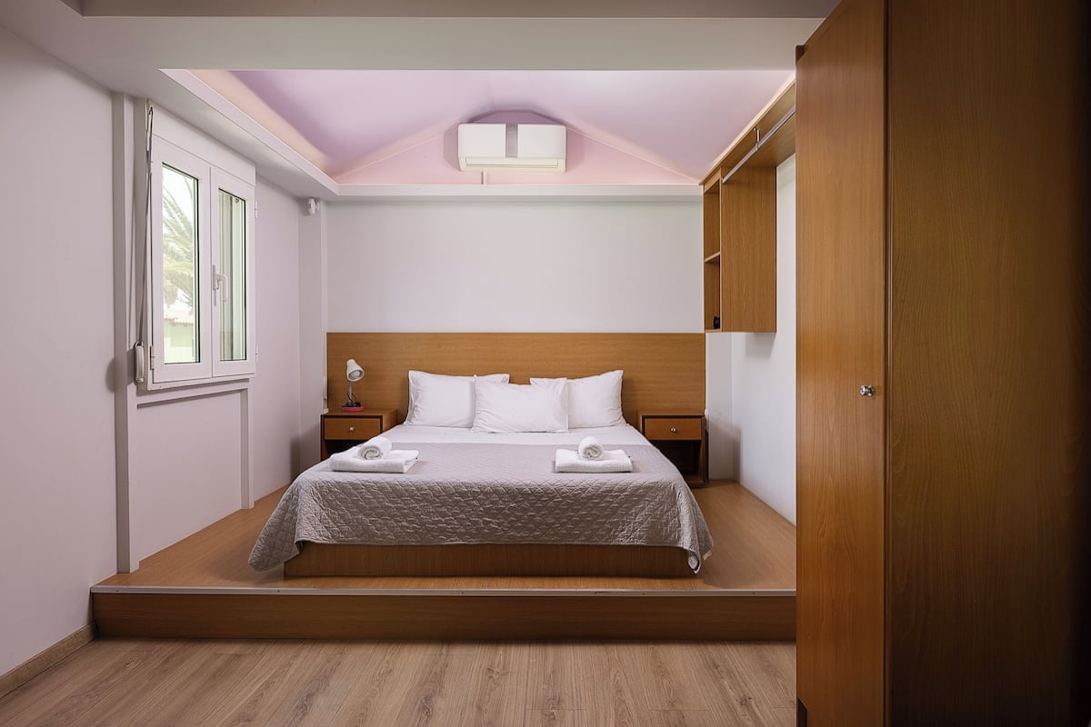 Camera da letto con un letto, comodini, una testiera in legno, una finestra e un lampadario.