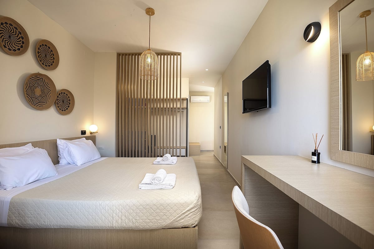 Una camera d'albergo moderna con un letto grande, una scrivania, una TV e decorazioni a parete.