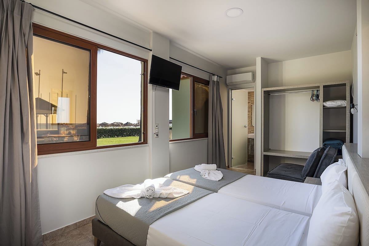 Una camera d'albergo con un letto, una televisione, un armadio e una finestra con tende.